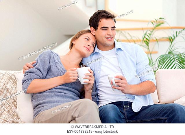 Lovely couple watching TV while drinking tea