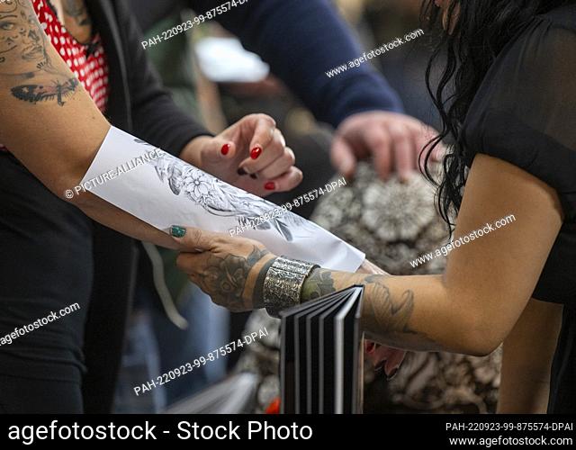 23 September 2022, Berlin: A visitor looks at a tattoo template on her arm at the 30th International Tattoo Convention Berlin