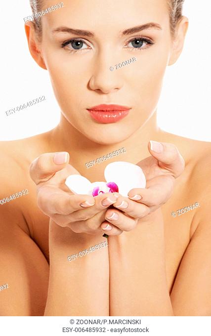 Beautiful naked woman holding white flower on hands