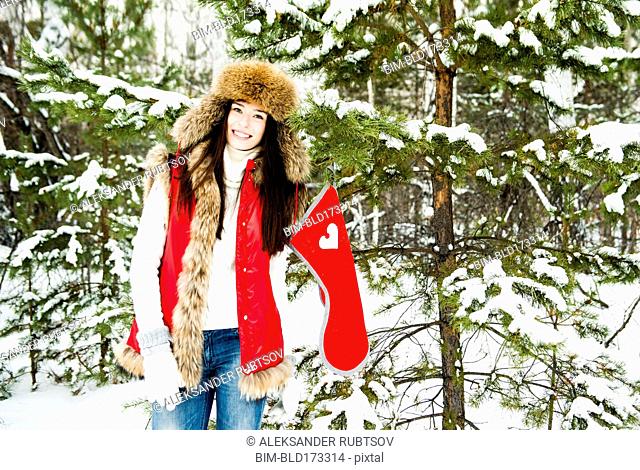 Caucasian girl hanging Christmas stocking on snowy tree
