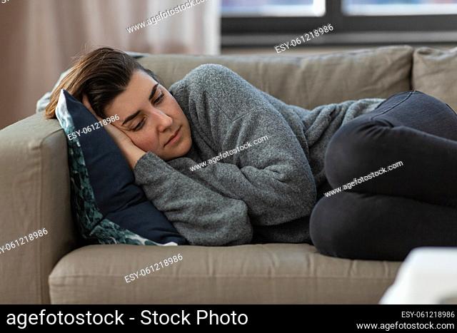 depressed woman lying on sofa at home