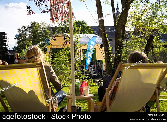 Zwei Liegestühle mit Personen und eine Bühne mit Ikea Fahne im Hintergrund. Während einer öffentlichen Open Air Veranstaltung des Unternehmens am Ufer der Lahn...
