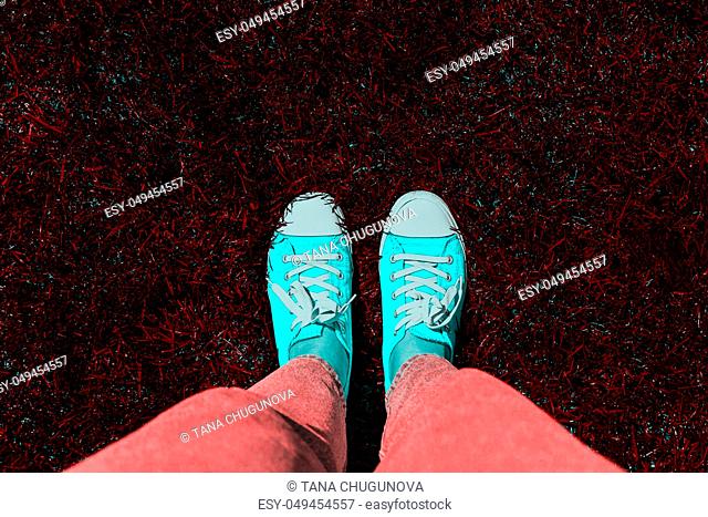 Legs in old sneakers on grass. View from above. Style: abstraction, illustration, monochrome, neon