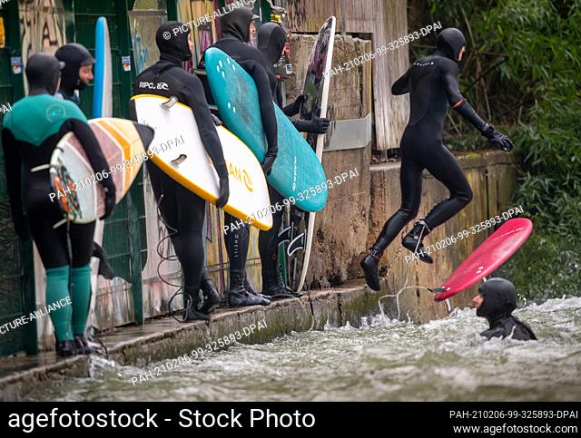 06 February 2021, Bavaria, Munich: Surfers with their colourful boards are waiting in the English Garden, in the heart of the Bavarian capital