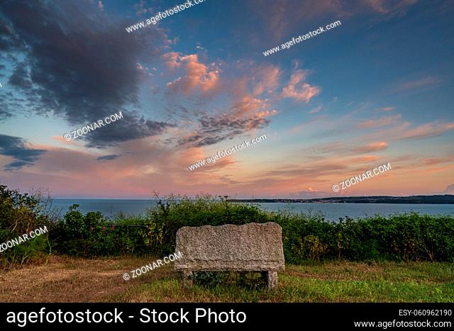 Evening clouds over a bench in Daddyhole Cove, Torquay, Torbay, England, UK