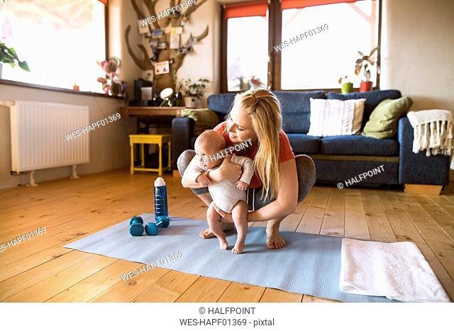Mother with baby and dumbbells at home