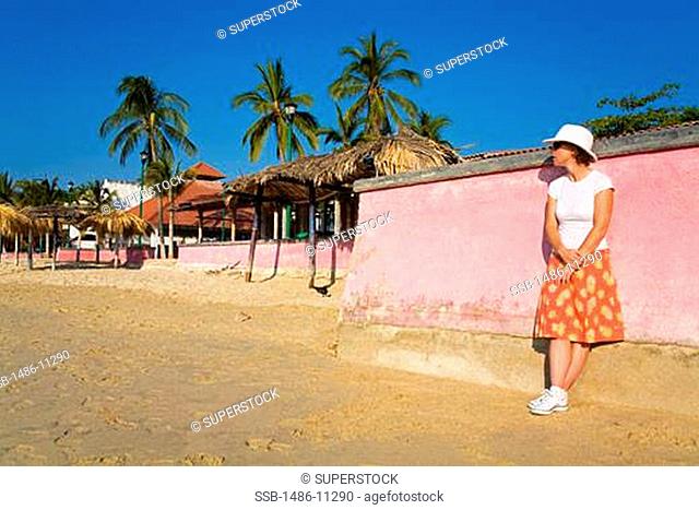 Woman leaning against a wall on the beach, Santa Cruz Beach, Santa Cruz, Huatulco, Oaxaca State, Mexico