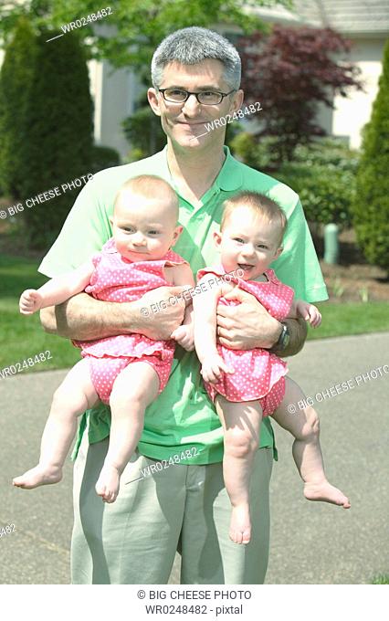 A father holding his two babies outdoors