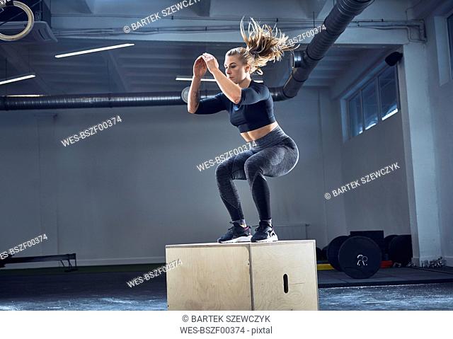 Athletic woman doing box jump exercise at gym