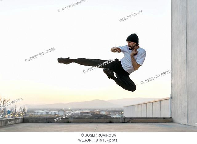 Man doing breakdance in urban concrete building, jumping mid air