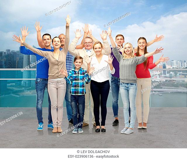 family, tourism, travel and people concept - group of smiling men, women and boy waving hands over singapore city waterside background