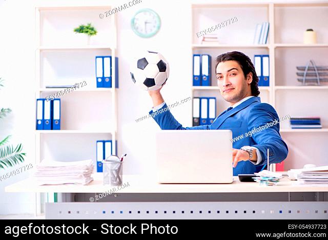 Young handsome businessman with soccer ball in the office