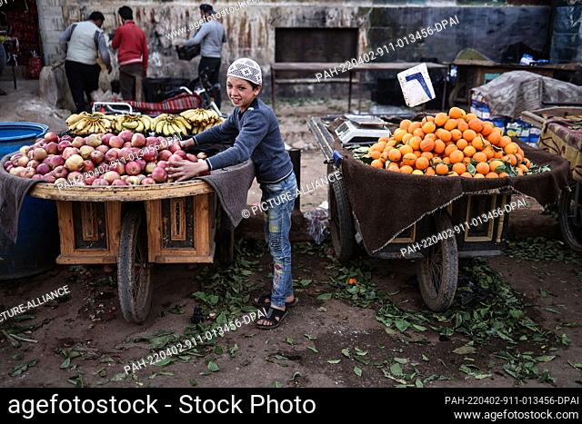 02 April 2022, Syria, Idlib: A young Syrian vendor sells fruits at a local market in Idlib, on the first day of the Muslim's holy fasting month of Ramadan
