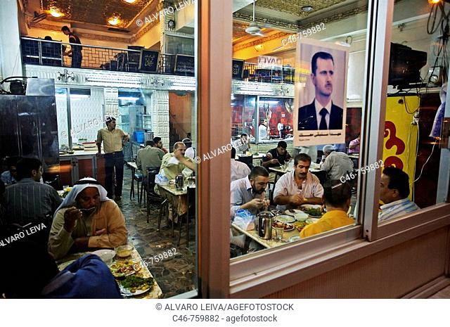 Restaurant after sunset during Ramadan with a portrait of Syrian president Bashar al-Assad, new city, Aleppo, Syria