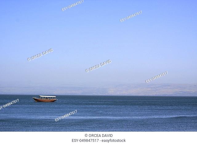 boat am the sea of galilee in a summer day with blue sky and water with the golan hight in the background