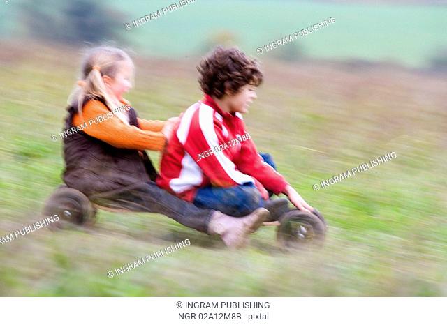 Boy with a girl riding a mountian board in a field