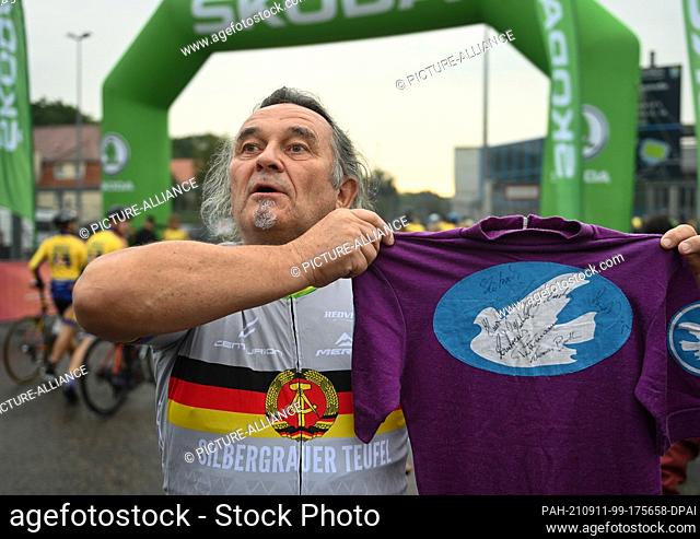 11 September 2021, Saxony, Chemnitz: Former cyclist and Peace Ride participant Thomas Barth holds a jersey with the Peace Ride logo in his hand before the start...