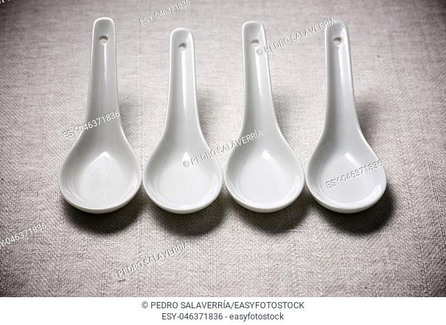 Small white spoons on a white tablecloth