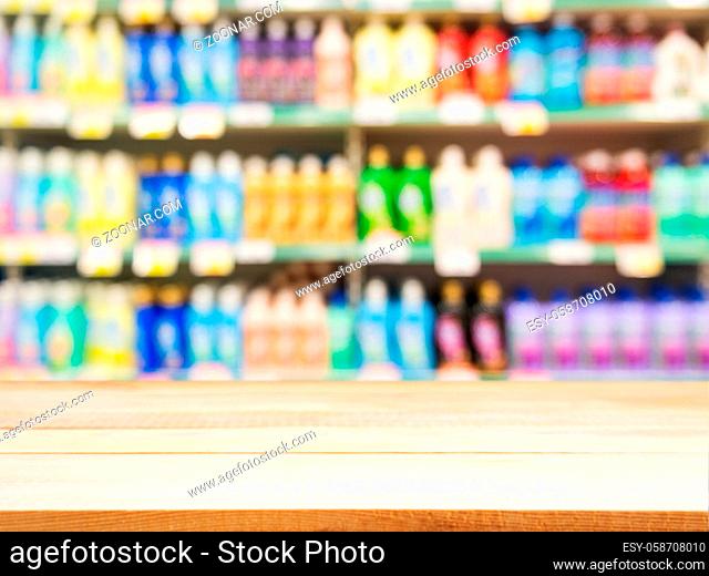 Wooden board empty table in front of blurred background. Perspective light wood over blur colorful supermarket products on shelves