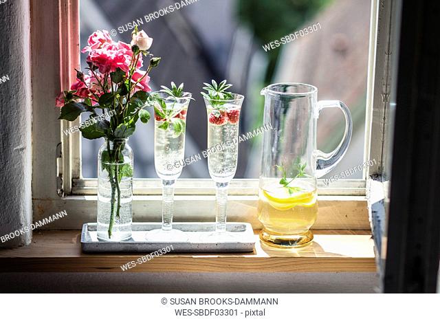 Two Champagne glasses of may wine with raspberries on window sill