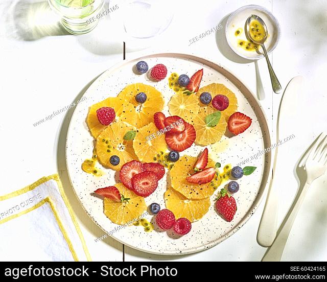 Thinly sliced oranges with strawberries, blueberries, passionfruit and raspberries