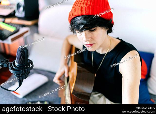 Female musician playing guitar while recording at studio