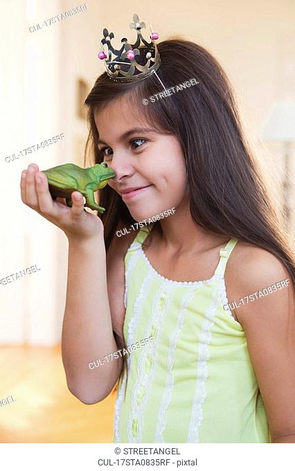 girl wearing crown playing with toy frog