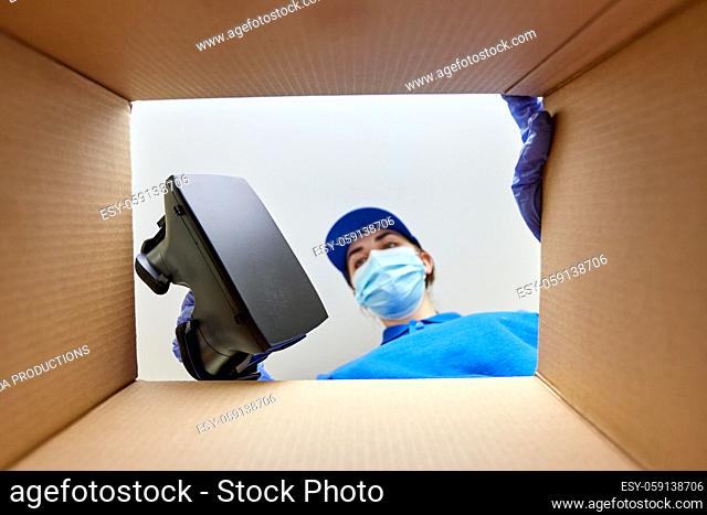 woman in mask packing vr glasses to parcel box