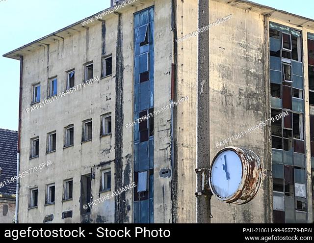 10 June 2021, Mecklenburg-Western Pomerania, Pasewalk: A weathered clock on the grounds of a former GDR agricultural enterprise in front of a dilapidated...
