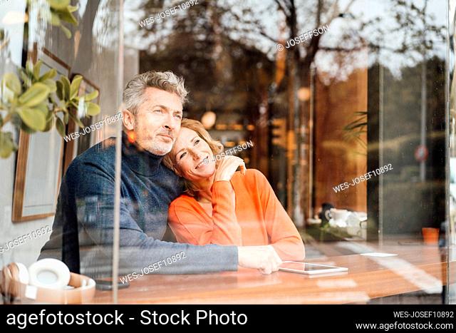 Smiling woman with man sitting in cafe seen through glass