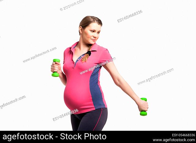 Young pregnant woman making exercise with dumb bells isotated on white