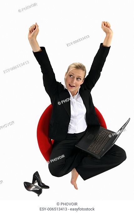 businesswoman sitting on a chair with her laptop and raising her hands