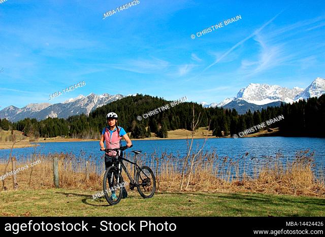 young woman cycling with mountain bike at Geroldsee in the Buckelwiesen near Krün, Germany, Bavaria, Upper Bavaria, Isar Valley, road, path, bicycle