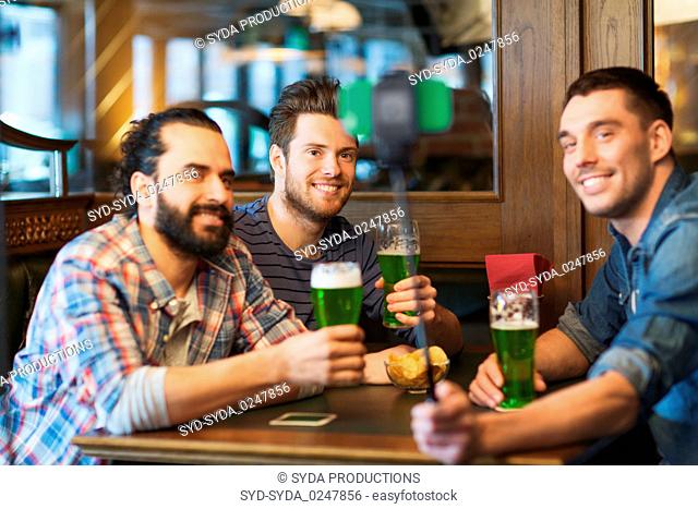 friends taking selfie with green beer at pub