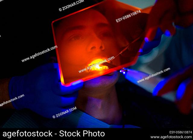Dentistry. Dentist and patient. Light curing seal. UV dental lamp and orange protect glass