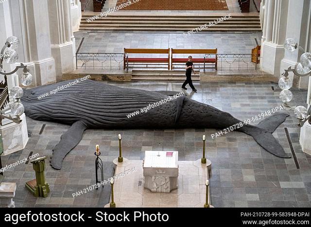 28 July 2021, Mecklenburg-Western Pomerania, Greifswald: Gil Shachar, an artist from Isarel, is setting up a whale sculpture of a humpback whale in St
