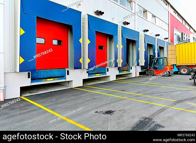 Forklift at cargo dock of big warehouse