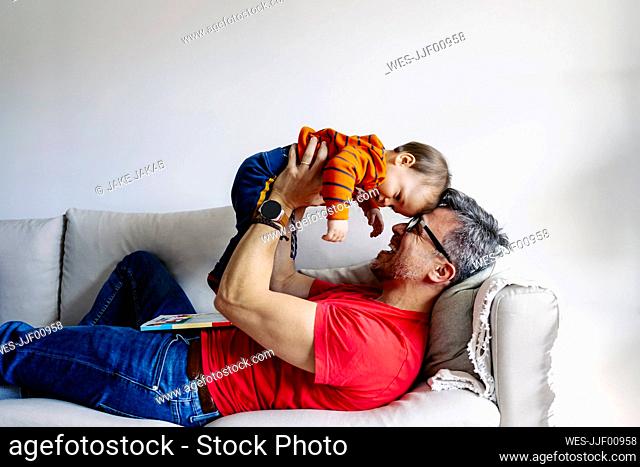 Happy father playing with son on sofa at home