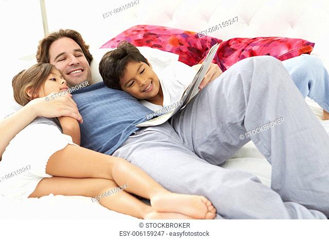 Father And Children Relaxing In Bed Together