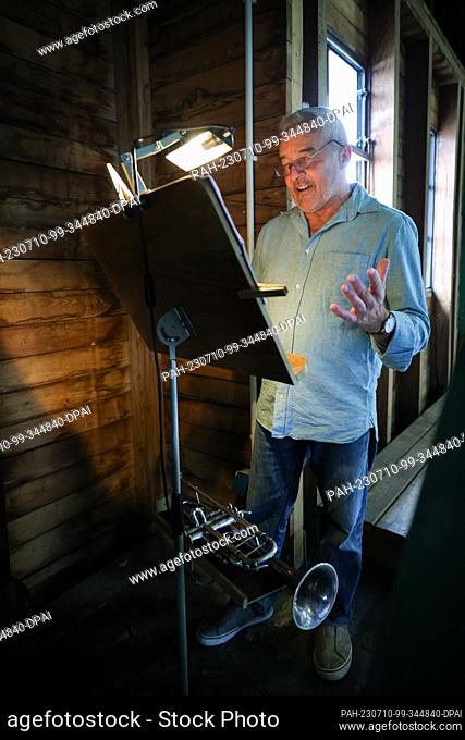PRODUCTION - 29 June 2023, Hamburg: Horst Huhn, tower trumpeter in Hamburg's Michel, stands in front of a music stand looking for a chorale