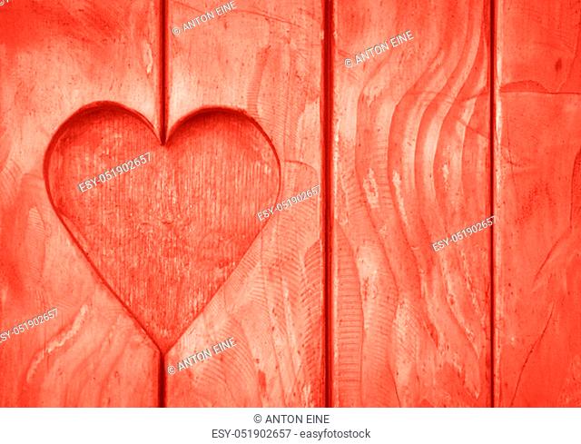 Close up one heart shape, symbol of love and romance, wood carved cut in wooden planks texture background, coral pink painted window shutter