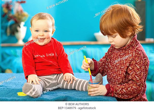 Red-haired girl feeding her younger sister