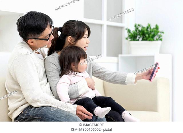 Family with one child looking at mobile phone and taking pics together
