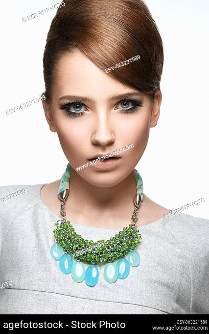 Beautiful fashionable girl with smooth hair and original decoration around her neck. Model in white. Beauty face. Picture taken in the studio on a white...