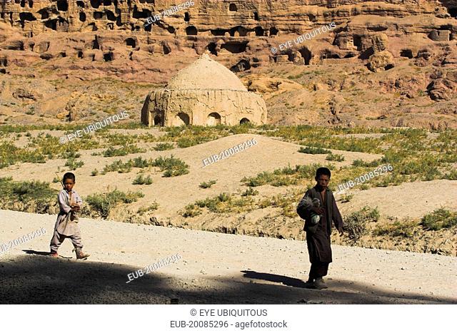 Boys walk past tomb near empty niche where the famous carved Budda once stood (destroyed by the Taliban in 2001)