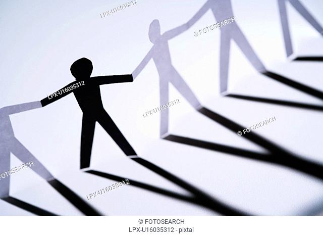 One black cutout paper person holding hands with group of white people