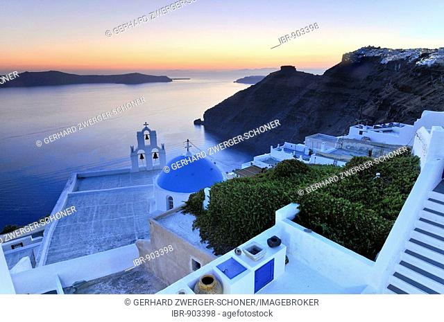 Stairway leading down to a white Greek church with a blue dome and a bell tower at sunset, Firostefani, Santorini, Cyclades, Greece, Europe