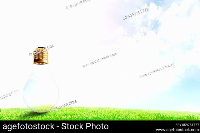Electric light bulb against summer cloudy sky