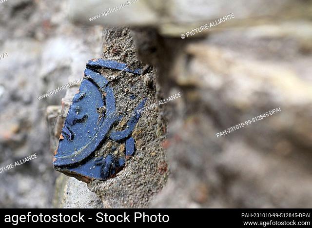 10 October 2023, Brandenburg, Potsdam: A shard of a tiled stove protrudes from the wall of the former foundation of a water mill in the excavation site on the...