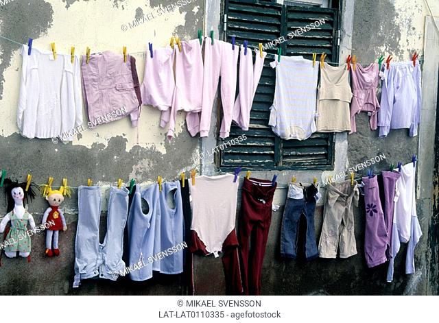 Street. House. Washing line. Two lines of clothes pegged onto line. Children's clothes